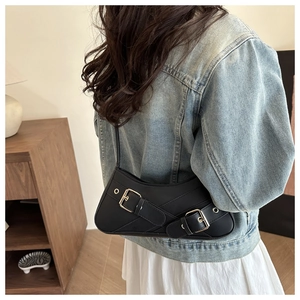 Détail du sac vintage noir avec boucles métalliques et texture en cuir lisse