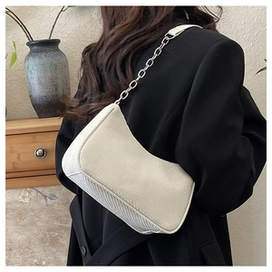 Detail of cream twill woven underarm bag with chunky silver metal chain strap