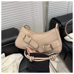 Détail du sac beige avec boucles dorées et bandoulière à nœud en cuir synthétique