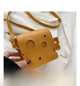 Detail of cheese-shaped yellow mini crossbody bag with unique hole design and PU texture