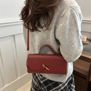 Burgundy woven leather crossbody bag with gold knot clasp shown on a model