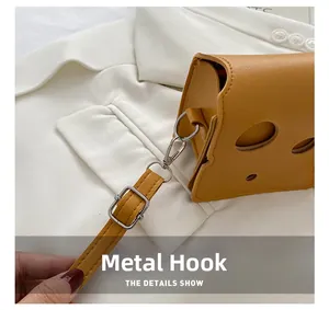 Detail of cheese-style mini crossbody bag with silver rotating hook and leather texture