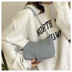 Close-up of light blue crescent bag with silver chain and textured fabric detail