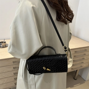 Elegant black woven crossbody bag with golden buckle and adjustable strap on a model