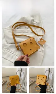 Detail of yellow cheese-shaped crossbody bag with hole pattern and mini charm