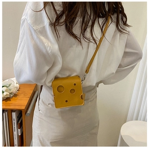 Detailed view of creative yellow cheese shaped crossbody bag with hollow hole design