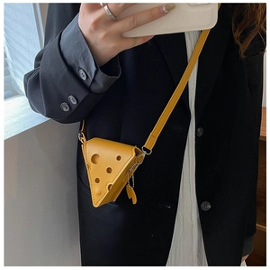 Detail of yellow cheese-shaped crossbody bag with hole design and matching strap on model