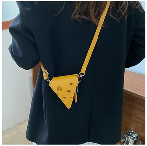 Model wearing a creative yellow cheese-shaped mini crossbody bag over a black blazer