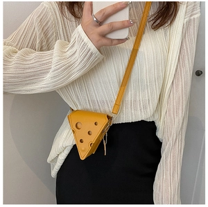 Detail of yellow cheese-shaped mini crossbody bag with creative hole design and gold zipper
