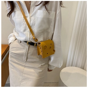 Detailed view of cheese slice crossbody bag in bright yellow with circular cutout design