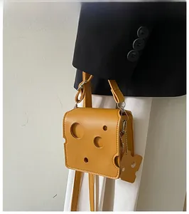 Detail of creative yellow cheese shaped crossbody bag with hollow hole design and strap