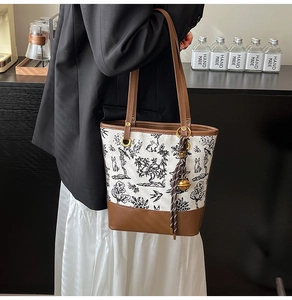 Detail of vintage canvas tote bag featuring brown leather trim and retro embroidery
