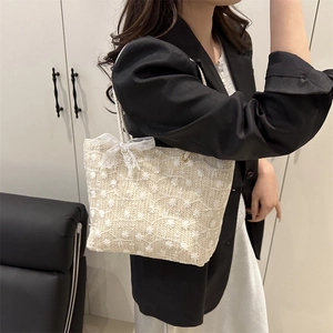 Sac fourre-tout en paille avec broderie marguerite et nœud en dentelle porté de côté