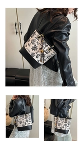 Detail of French toile print tote bag featuring black leather trim and tassel accent