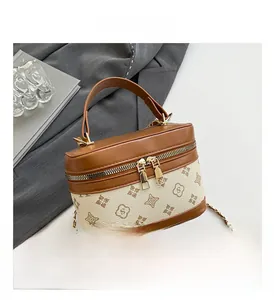 Close-up of hard square box bag featuring vintage floral monogram and gold chain strap