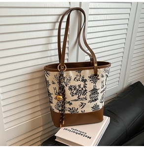 Détail du sac cabas en toile avec imprimé paysage, garniture en cuir et breloque clochette dorée