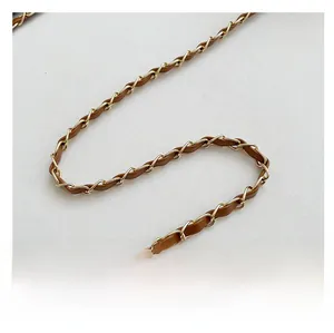 Close-up of golden chain strap interwoven with brown leather for luxury handbag