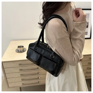 Dettaglio di una borsa tote in pelle nera con tasche a patta e finiture argentate