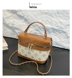 Detail of monogram patterned crossbody box bag with gold chain and leather handle