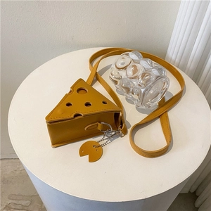 Mini cheese shaped yellow crossbody bag with holes and leather strap on white surface
