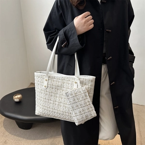 Elegant white tweed tote bag with gold rivets and matching mini pouch on a modern handle