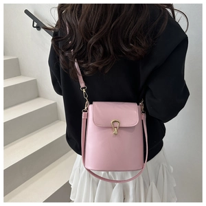 Detail of pink leather bucket bag showing the unique gold circular metal buckle closure