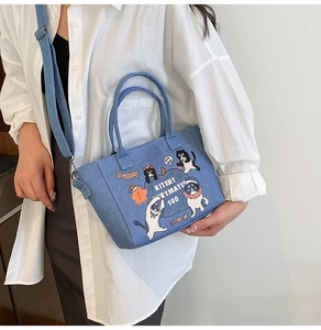 Detailed view of the denim tote bag with cat and gingerbread man cartoon prints