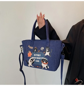 Detail of blue denim tote bag with cat illustration and adjustable shoulder strap