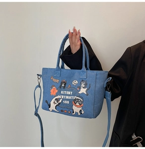 Detail of blue denim tote bag with cute cat illustrations and adjustable shoulder strap