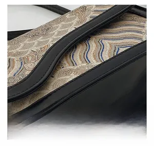 Detailed close-up of precise stitching and traditional cloud pattern on a leather bag