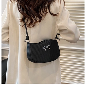 Dettaglio borsa nera con fiocco argento su modella con completo bianco elegante