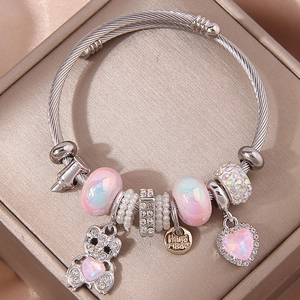Detail van kralenarmband met glinsterende beer en roze hartvormige hangers