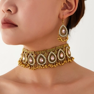 Detail of vintage boho jewelry set featuring pink teardrop gems and gold beaded tassels