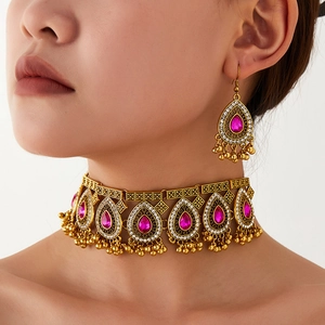 Macro detail of bohemian choker and earrings set with red teardrop stones and gold filigree