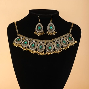Macro detail of vintage emerald pear-shaped gemstone jewelry set with gold bead tassels