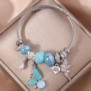 Close-up of wire rope charm bracelet with blue enamel butterfly and heart charms in a gold box