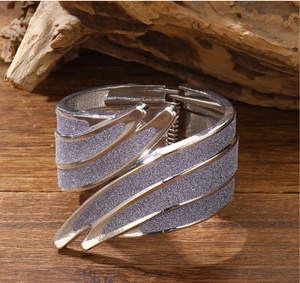 Detail van zilveren engelenvleugel armband met lavendel glitter op een houten achtergrond