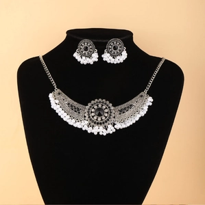 Detail van bohemien ketting en oorbellen met zwarte stenen en parelkwastjes