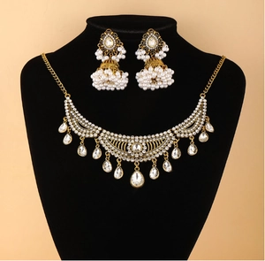 Détail d'une parure ethnique vintage dorée avec diamants, perles et boucles Jhumka
