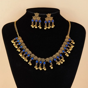 Detail of vintage gold jewelry set with blue gems and intricate floral carving