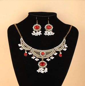 Détail d'un ensemble collier vintage avec pierres rouges et pompons de perles blanches