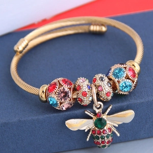 Détail du bracelet câble doré avec strass colorés et breloque en forme d'abeille