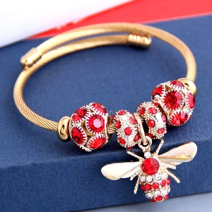 Vue macro d'un bracelet en fil doré torsadé orné d'une breloque abeille en cristaux