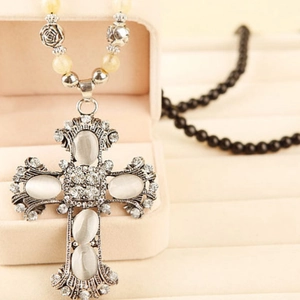 Macro detail of retro cross necklace with white cat eye stones and sparkly rhinestones
