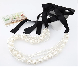 Détail d'un collier de perles multicouche avec un élégant nœud en ruban de satin noir