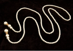Détail d'un long collier de perles multicouches avec des accents dorés sertis de diamants