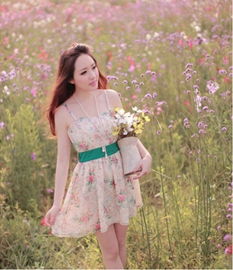 Détail de mini robe à fleurs avec fines bretelles et ceinture verte au milieu