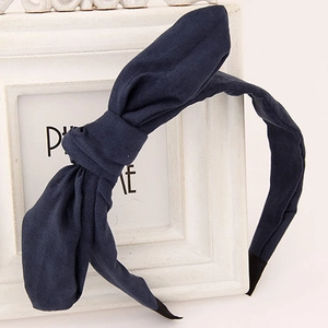 Solid navy blue fabric headband with large rabbit ear bow on a white display rack
