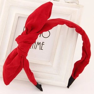 Detail of red bow headband with twill texture leaning on a white photo frame