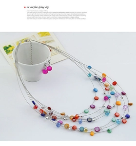 Detail of bohemian layered beaded necklace and pink drop earrings with silver wires